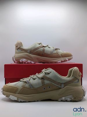 a pair of beige sneakers sitting on top of a red box