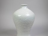 un vase blanc posé sur une table, sur fond gris