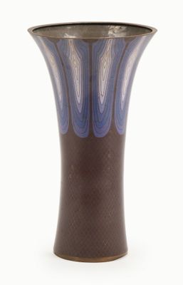 a blue and brown vase sitting on a white surface