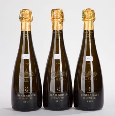 trois bouteilles de champagne posées les unes à côté des autres sur une surface blanche