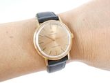 a woman ' s wrist that has a gold watch on it