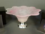 a pink glass bowl sitting on a table next to a black box