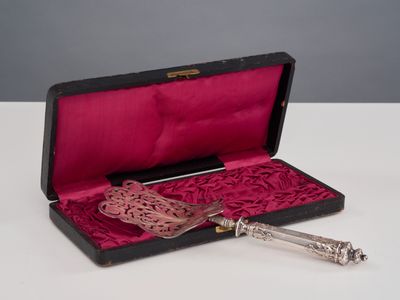 une cuillère en argent dans une boîte rouge avec un couvercle rose