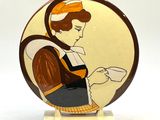 une photo d'une assiette en céramique sur laquelle figure une femme tenant une tasse