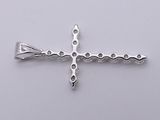 a silver cross on a white surface with a white background