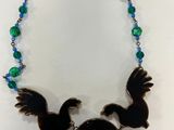 a close up of a necklace with two birds on it