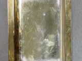brass plate with a mirror in the middle of it on a gray surface