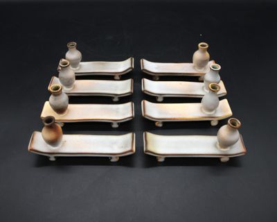 quatre pièces de poterie posées sur les plateaux posés sur la table