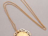 a gold necklace with a coin in the middle of it
