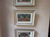 trois tableaux accrochés au mur au-dessus des toilettes