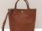 un petit sac à main marron posé sur une surface blanche