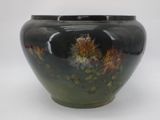 a black vase with flowers painted on it on a white background