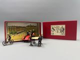 two figurines of people in a red box with a picture of a horse drawn carriage