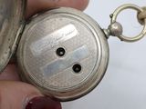 a person holding a silver pocket watch in their hand