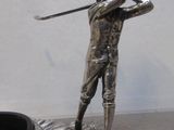 une statue représentant un homme tenant un club de golf, perché sur un rocher