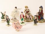 five figurines of people sitting on top of a table