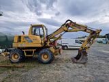 un tracteur jaune garé sur la terre battue