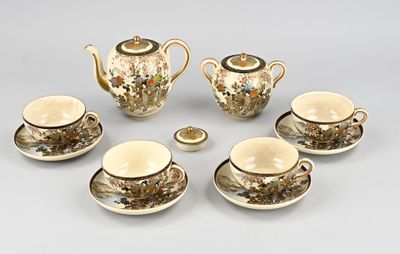 cinq tasses et soucoupes ainsi qu'une théière sur la table