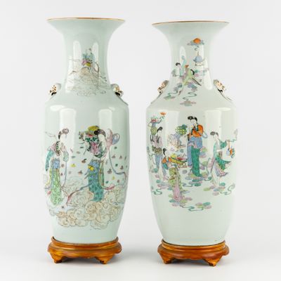 pair of chinese vases with figures on them sitting on a table