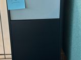 a black refrigerator with a blue sticker on it in the corner of a room