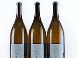 three bottles of wine sitting next to each other on a white surface