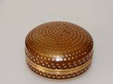 a small round box with gold dots on it