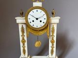 a white and gold clock sitting on top of a table