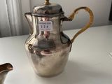 a silver tea pot and a silver pitcher on a white table