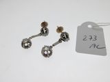three silver and gold earrings with a price tag on a white table