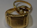 a gold ring with a pearl in it on a white surface