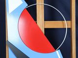 a painting on a easel with a red circle and a blue triangle