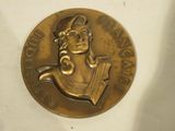 une médaille d'or représentant une femme portant un chapeau de marin