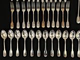 a lot of silver spoons and forks on a black surface