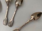 four spoons and a spoon rest on a white surface