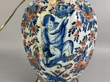 a blue and white vase on a table with a lamp on it
