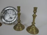 three brass candlesticks and a silver plate on a table