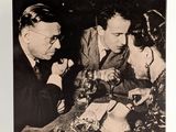 une photo en noir et blanc représentant deux hommes et une femme assis à une table