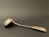 an old spoon sitting on top of a table next to a black surface