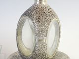a silver vase on a saucer with a plate underneath it