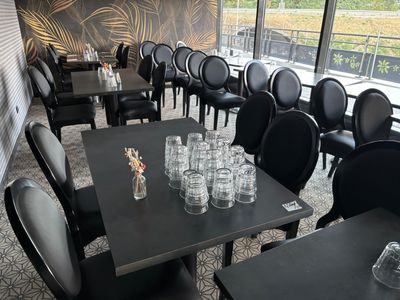 Des tables et des chaises sont disposées dans un restaurant offrant une vue sur l'extérieur.