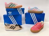 trois paires de baskets Adidas sont posées sur une boîte bleue