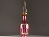 a pink glass bottle with a gold top on a table