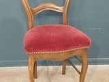 une vieille chaise en bois dont l'assise est recouverte de velours rouge