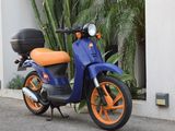 a blue and orange scooter parked on the side of the road
