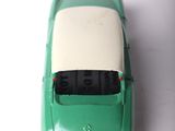 a green toy car with a white top on a white surface