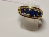 an image of a gold ring with blue stones on a white surface