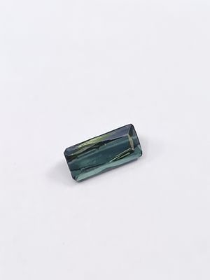 une tourmaline verte de forme rectangulaire posée sur un fond blanc