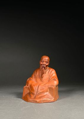 une vieille figurine sculptée représentant un homme assis sur une chaise