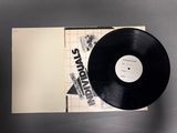 a black vinyl record sitting on top of a table next to a piece of paper