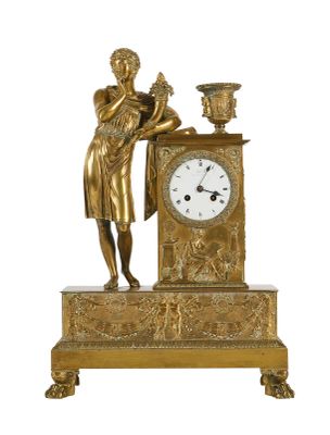 une horloge en or sur laquelle est représentée une femme tenant un vase
